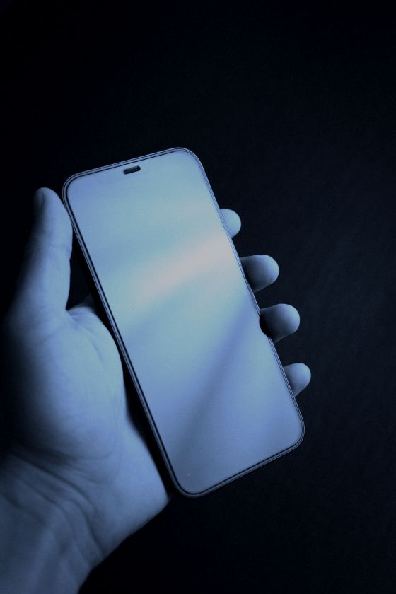 Mano sosteniendo un teléfono sobre fondo oscuro